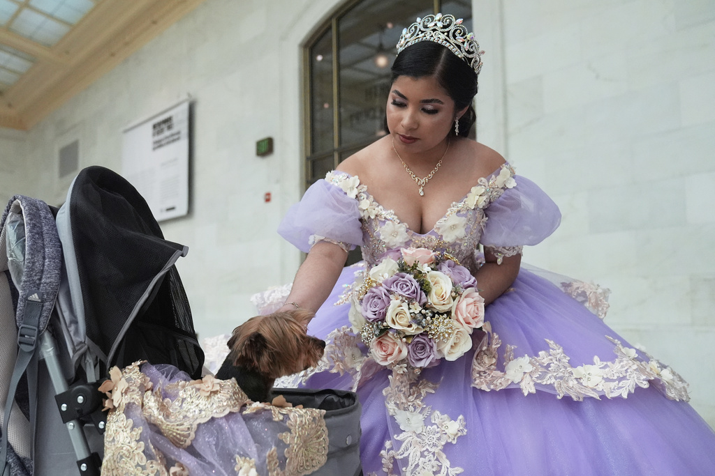 Leyla Portillo pets her dog Canela before the start of her quinceañera portrait session at City Hall in San Francisco, Monday, April 28, 2025. (AP Photo/Jeff Chiu)