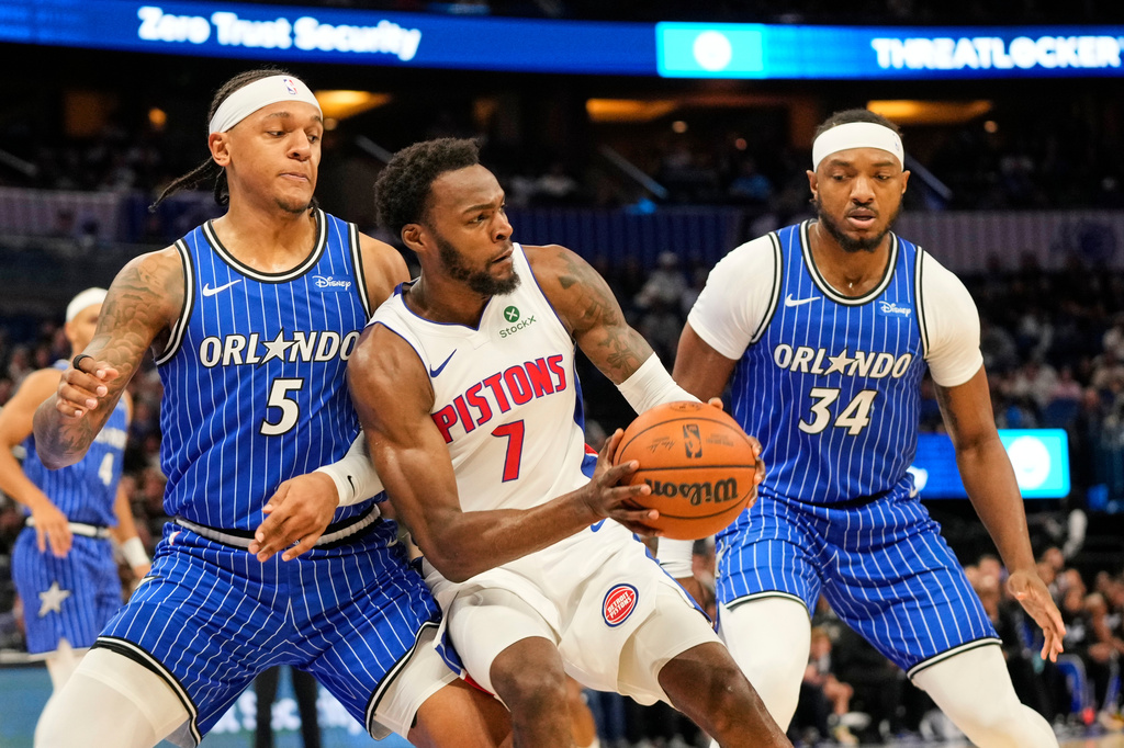 Detroit Pistons forward Paul Reed (7) looks to pass the ball as he gets caught between Orlando Magic forward Paolo Banchero (5) and center Wendell Carter Jr. (34) during the first half of an NBA basketball game, Monday, April 6, 2026, in Orlando, Fla. (AP Photo/John Raoux)