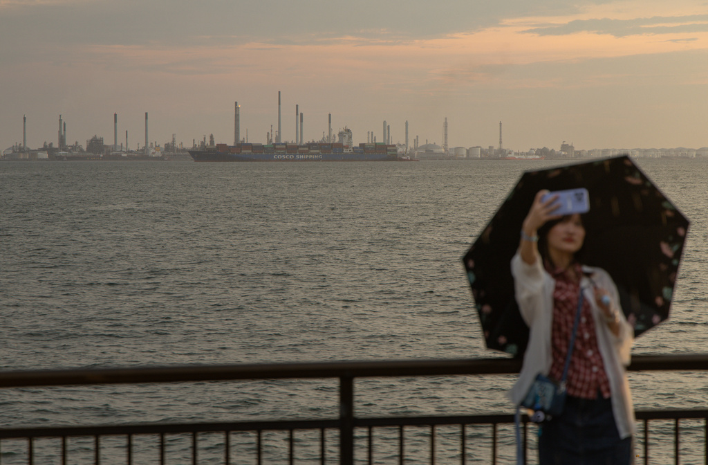 A visitor takes a selfie backdropped by Pulau Bukom Island from Singapore's Labrador Nature Reserve on Oct. 5, 2025. (AP Photo/Anton L. Delgado)