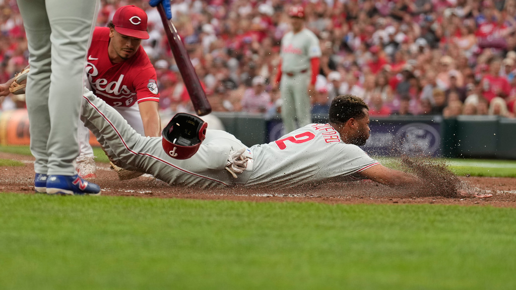 Philadelphia Phillies Justin Crawford dives in to home plate to score on a wild pitch as Cincinnati Reds pitcher Chase Burns, left, reaches in with a late tag during the second inning of a baseball game in Cincinnati, Wednesday, July 8, 2026. (AP Photo/Carolyn Kaster)