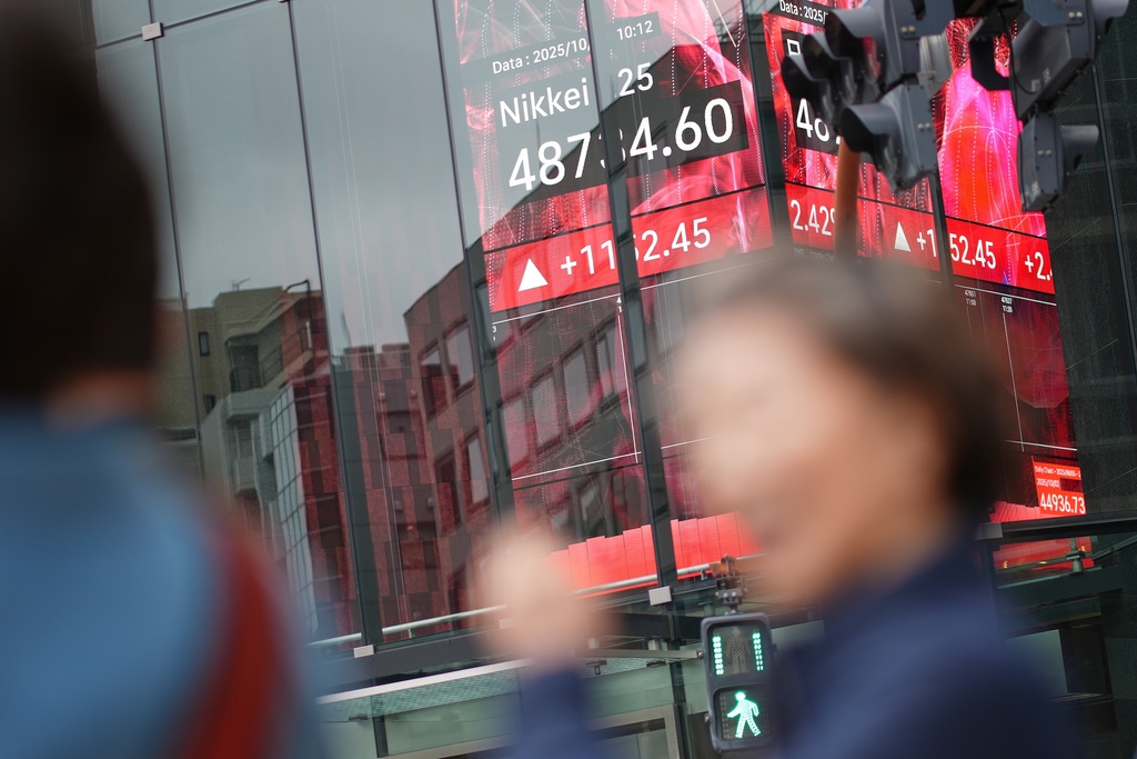 A person walks in front of an electronic stock board showing Japan's Nikkei index at a securities firm Monday, Oct. 20, 2025, in Tokyo. (AP Photo/Eugene Hoshiko)