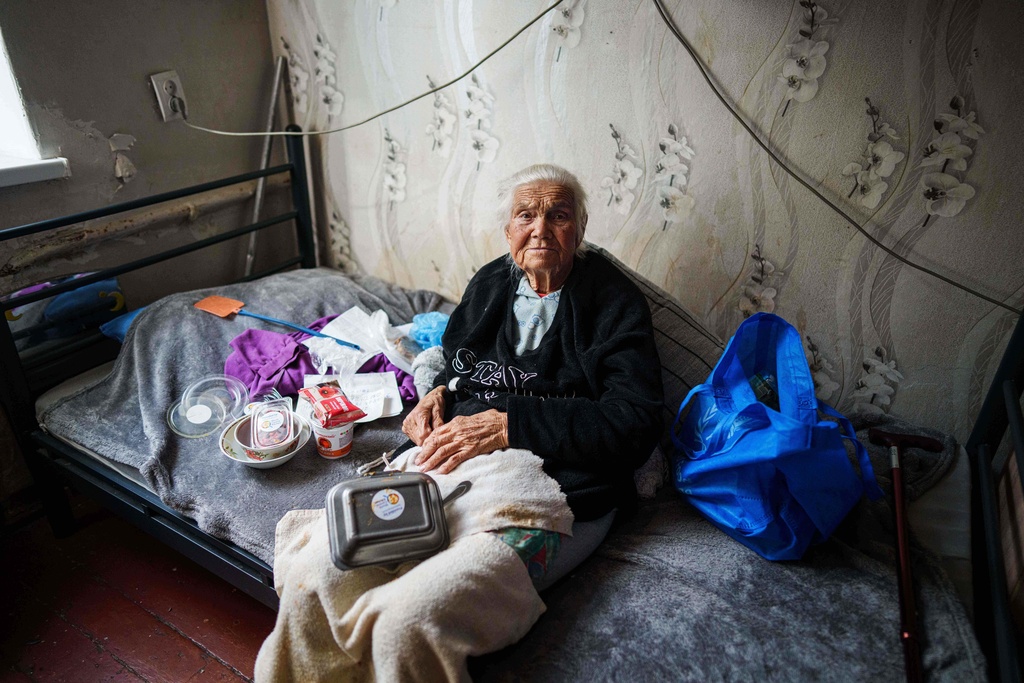 Olha, 81, sits on her bed at a hostel for the displaced in Dnipro, Ukraine, Wednesday, Oct. 8, 2025. (AP Photo/Evgeniy Maloletka)