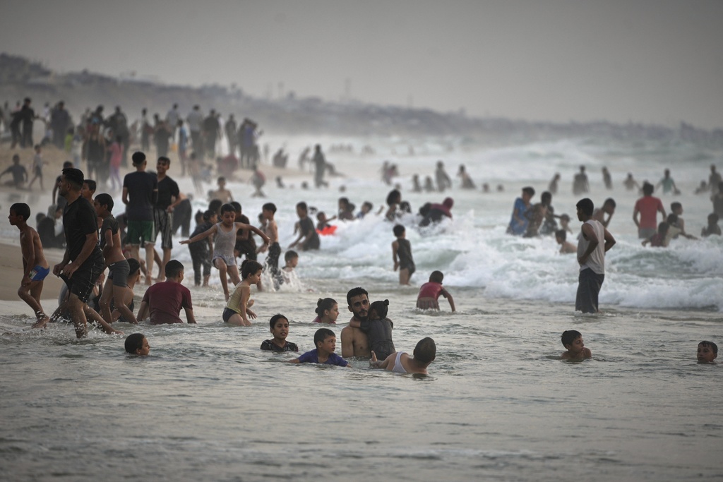 Palestinians cool off in the Mediterranean on a hot summer day near a tent camp by the seaside in Zawaida, central Gaza Strip, Friday, Aug. 22, 2025.(AP Photo/Abdel Kareem Hana)