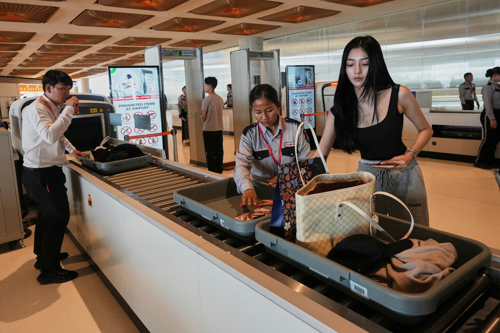 A passenger, right, attends to her belongings during a security check at the Techo International Airport on the outskirts of Phnom Penh, Cambodia, Tuesday, Sept. 9,2025. (AP Photo/Heng Sinith)