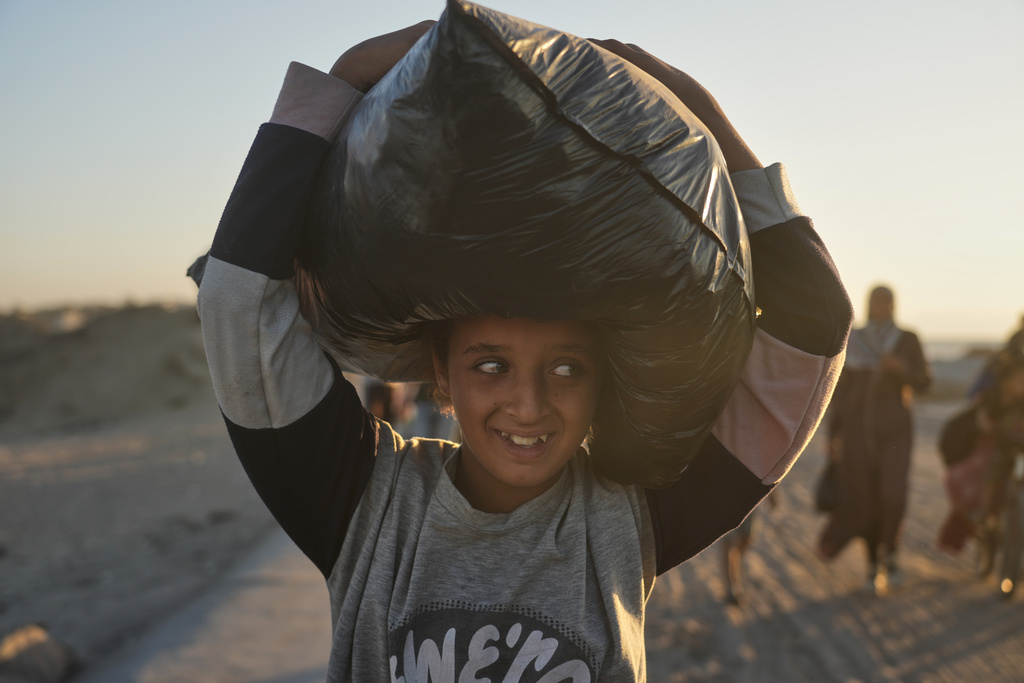 A displaced Palestinian girl carries a bag on her head as she walks along the coastal road near Wadi Gaza in the central Gaza Strip, heading toward Gaza City, Friday, Oct. 10, 2025, after Israel and Hamas agreed to a pause in their war and the release of the remaining hostages. (AP Photo/Abdel Kareem Hana)