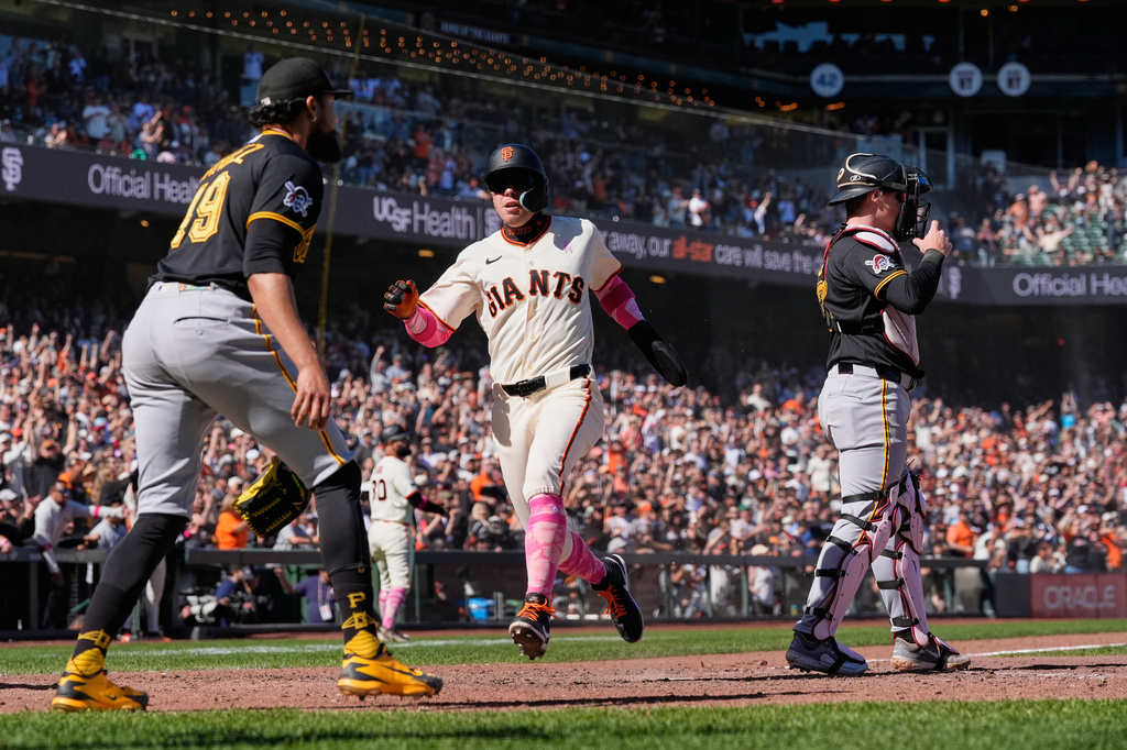 San Francisco Giants' Christian Koss, center, scores against the Pittsburgh Pirates on Willy Adames' single during the 10th inning of a baseball game Sunday, May 10, 2026, in San Francisco. (AP Photo/Godofredo A. Vásquez)