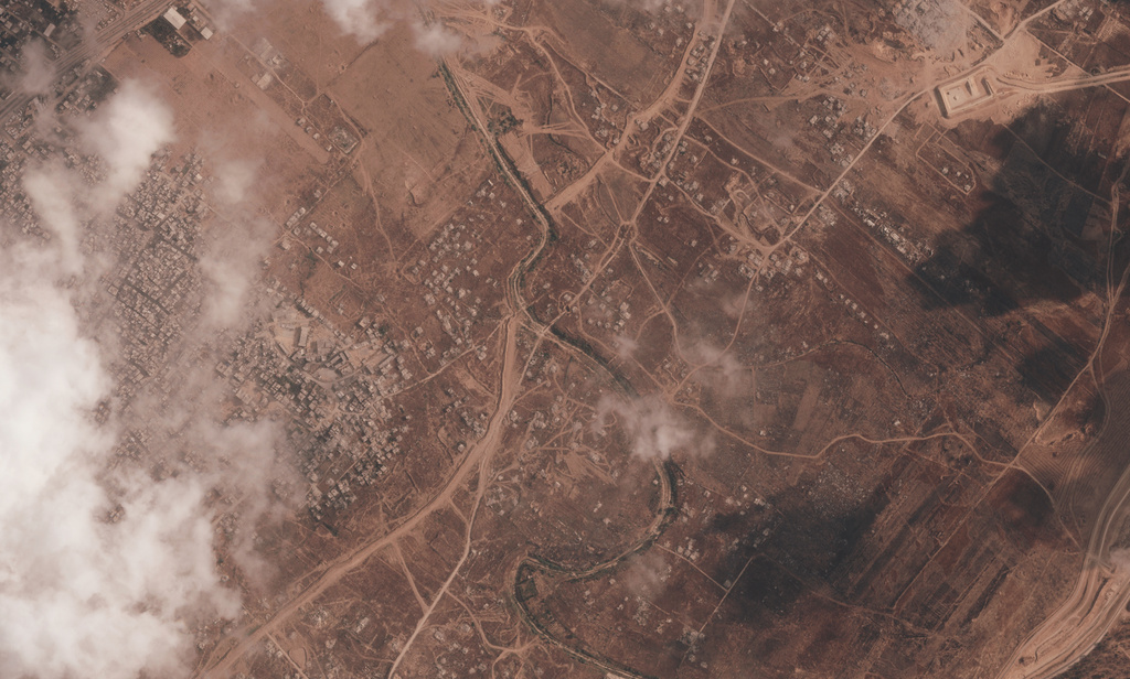 A satellite image from Planet Labs PBC shows a section of an earthen barrier being built by the Israeli military in the central Gaza Strip, July 7, 2026. The Bureij refugee camp is visible on the left, with the Wadi Gaza stream interrupting the barrier. An Israeli military base is on the other side. (Planet Labs PBC via AP)