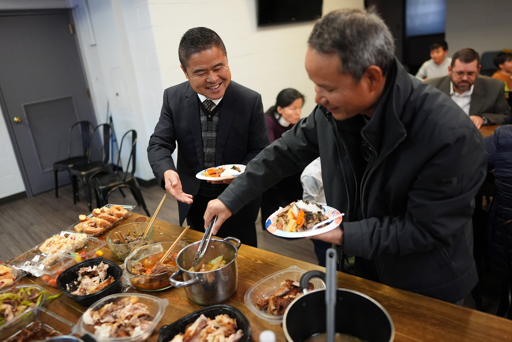 Former Chinese official Li Chuanliang, left, shares a meal with other members of the Mayflower Church, a Christian community which fled religious persecution in China, and American pastors who have welcomed the refugees, in Midland, Texas, Jan. 19, 2025. (AP Photo/Rebecca Blackwell)
