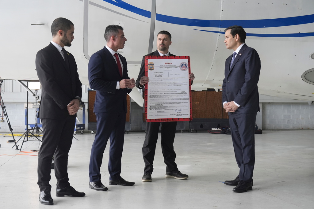 FILE - U.S. Secretary of State Marco Rubio, right, listens to Edwin F. Lopez, the attaché for DHS Homeland Security Investigations, second from left, next to the Venezuelan government airplane that Rubio announced is being seized by the U.S. during a news conference at La Isabela International Airport in Santo Domingo, Dominican Republic, Feb. 6, 2025. At left is Dominican Public Prosecutor Enmanuel Ramirez, and holding the "seized" sign is Robert Cunniff from the U.S. Department of Commerce. (AP Photo/Mark Schiefelbein, Pool, File)