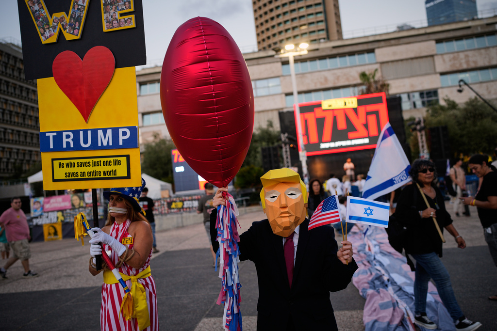 A woman wearing a mask depicting U.S. president Donald Trump attends a rally calling for the release of all hostages held in the Gaza Strip and urges a ceasefire, in Tel Aviv, Israel, Saturday, Oct. 4, 2025. ahead of the second anniversary of the Israel-Hamas war. (AP Photo/Ohad Zwigenberg)