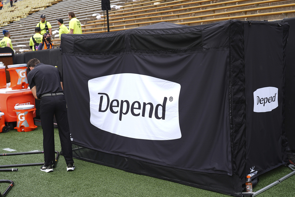 A field worker sets up equipment next to a tent containing a bathroom in the team box on the Colorado sideline before an NCAA college football game against Georgia Tech Friday, Aug. 29, 2025, in Boulder, Colo. (AP Photo/David Zalubowski)