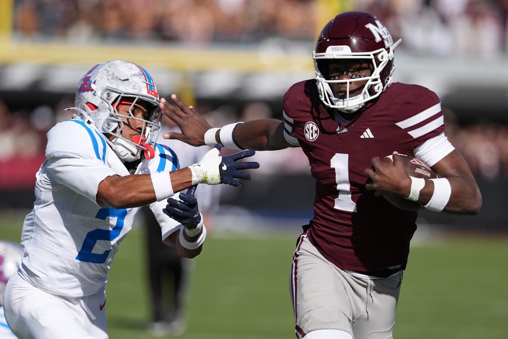 Mississippi State quarterback Kamario Taylor (1) stiff arms Mississippi cornerback Jaylon Braxton (2) as he runs for 22-yard touchdown during the first half of an NCAA college football game Frifday, Nov. 28, 2025, in Starkville, Miss. (AP Photo/Rogelio V. Solis)