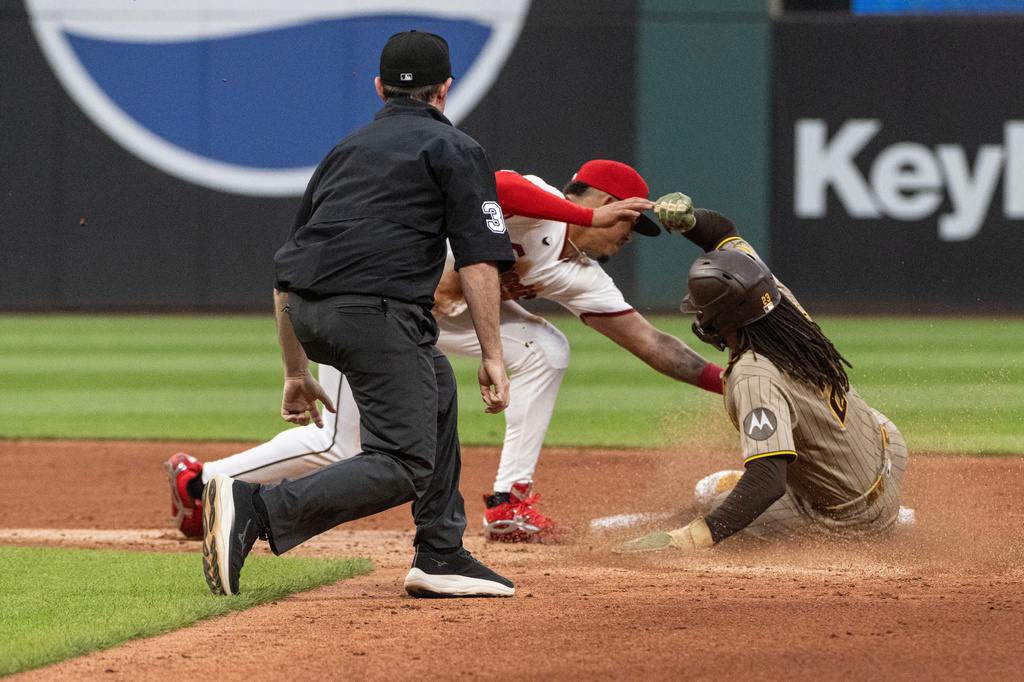 Cleveland Guardians' Angel Genao tags San Diego Padres' Fernando Tatis Jr. out on a sweat attempt as umpire Tyler Jones watches the play, during the third inning of a baseball game, Saturday, Aug. 15, 2026, in Cleveland. (AP Photo/Phil Long)