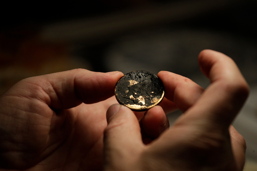 FILE - California Gold Marketing Group's Dwight Manley examines a gold coin, recovered from the S.S. Central America steamship that went down in a hurricane in 1857, in a laboratory, Jan. 23, 2018, in Santa Ana, Calif. (AP Photo/Jae C. Hong, File)