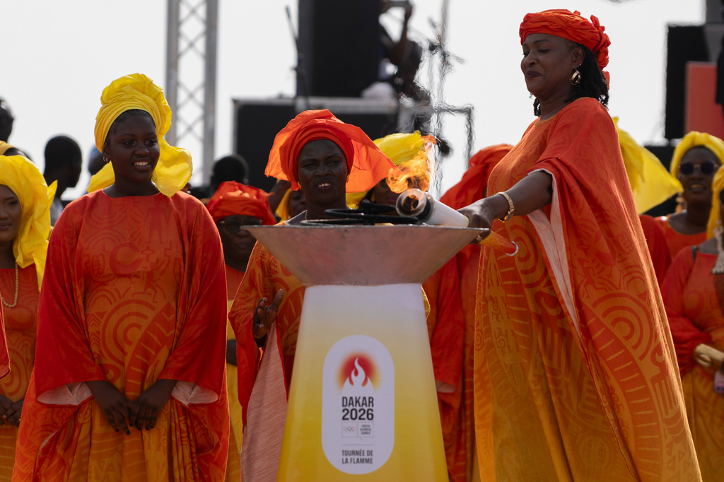 Senegalese basketball legend Mame Maty Mbengue lights a torch from the cauldron during a ceremony ahead of the Dakar 2026 Youth Olympic Games, in Dakar, Senegal, Saturday, Sept. 12, 2026. (AP Photo/Sylvain Cherkaoui)