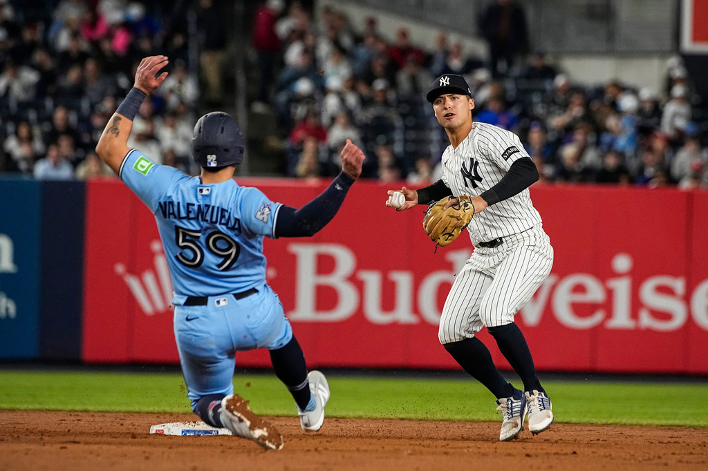 New York Yankees shortstop Anthony Volpe, right, throws to first base after forcing Toronto Blue Jays Brandon Valenzuela (59) out at second base on a double play, during the ninth inning of a baseball game, Thursday, May 21, 2026. in New York. (AP Photo/Eduardo Munoz Alvarez)