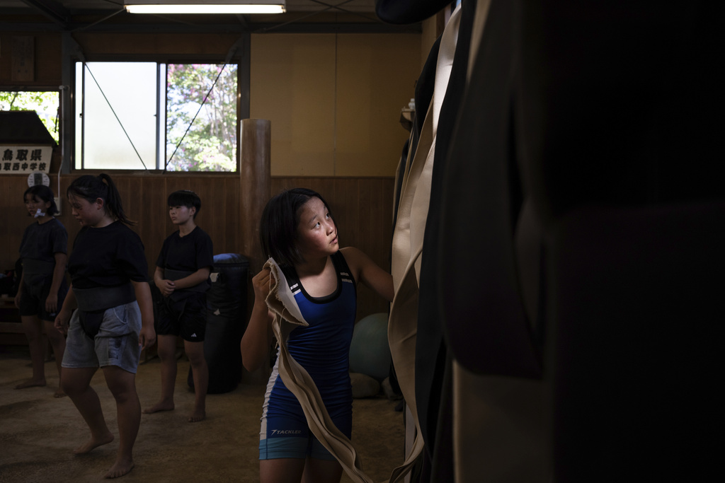 A wrestler picks up a belt prior to a practice session at a sumo camp in Tottori Johoku High School in Tottori, Japan, on July 28, 2025. (AP Photo/Louise Delmotte)
