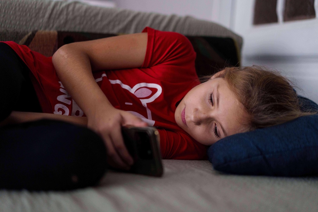 A girl watches videos at a hostel for the displaced in Dnipro, Ukraine, Wednesday, Oct. 8, 2025. (AP Photo/Evgeniy Maloletka)