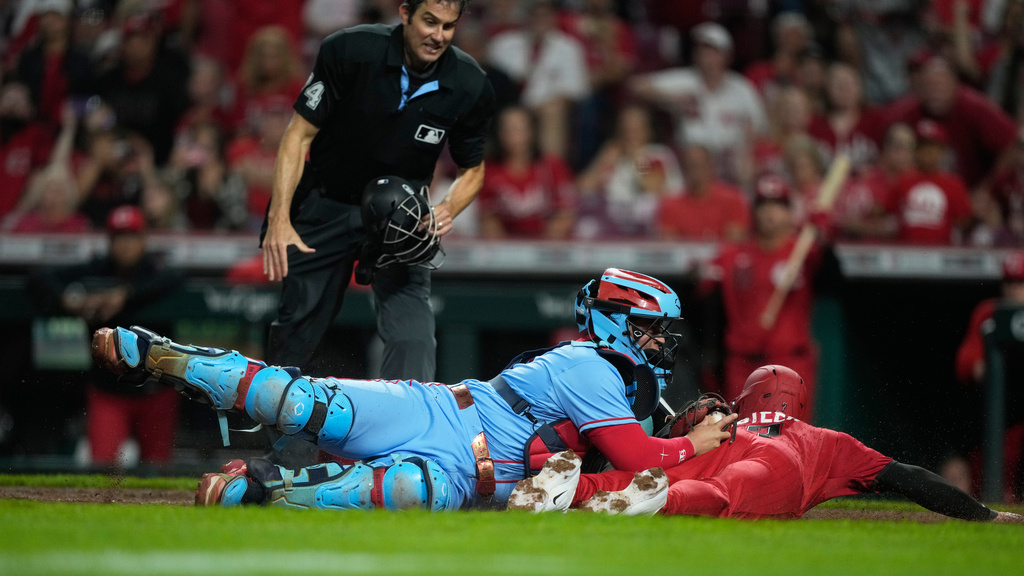 Home plate umpire John Tumpane looks on as Cincinnati Reds' Spencer Steer, right, is safe as he dives into home plate to score the game winning run on a single hit by Blake Dunn as St. Louis Cardinals catcher Yohel Pozo, center, follows with the late tag in the eleventh inning of the second baseball game of a doubleheader in Cincinnati, Saturday, May 23, 2026. (AP Photo/Carolyn Kaster)