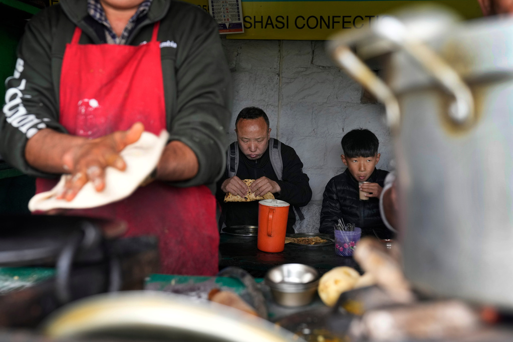 Sonam Tashi and his son, Kunga Tenzin, eat breakfast at a roadside stall in Mcleodganj near Dharamshala, India, March 7, 2025. (AP Photo/Manish Swarup)