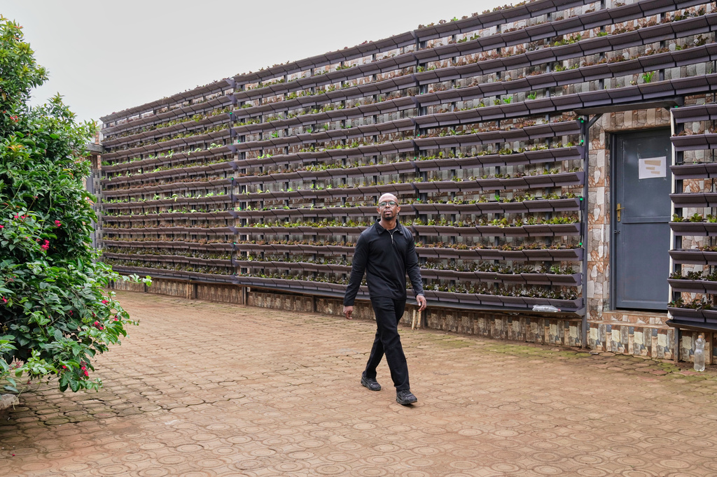 Christian Irakoze, co-founder of Eza Neza, or "Grow Well," a local company that sets up vertical farms in the city and describes them as scalable, walks inside a home compound in Kigali, Rwanda, March 18, 2026. (AP Photo/Brian Inganga)