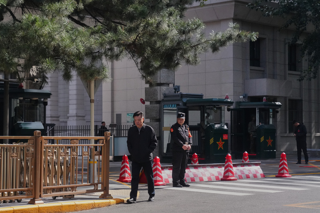 A man walks by Chinese security personnel guarding the entrance to the Jingxi Hotel where the Communist Party's Central Committee is holding its fourth plenum, in Beijing, Monday, Oct. 20, 2025. (AP Photo/Andy Wong)