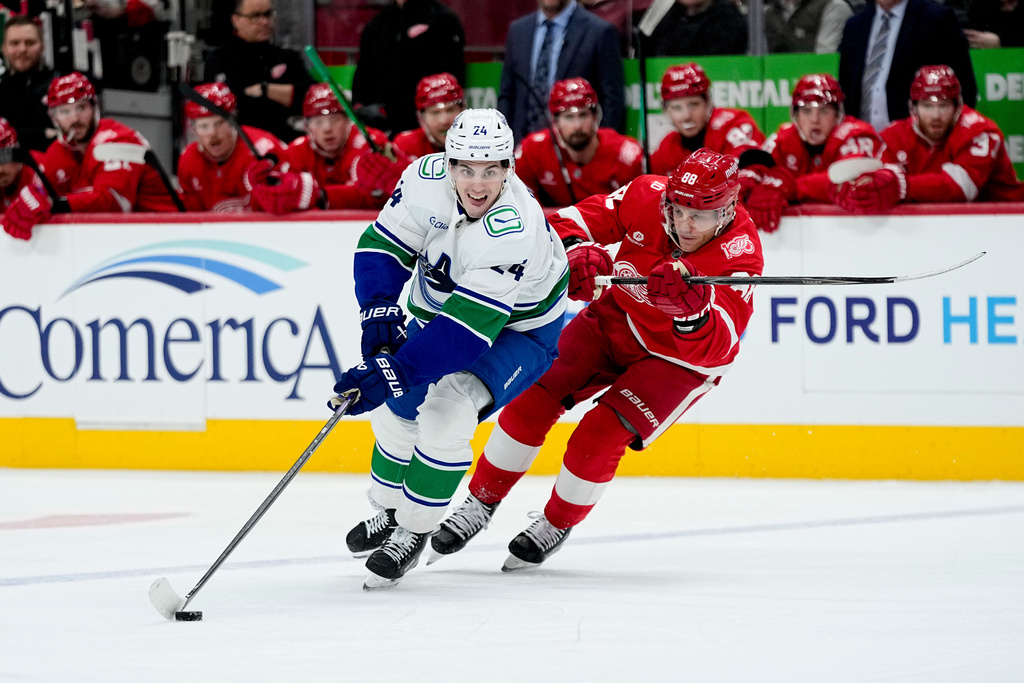 Vancouver Canucks defenseman Zeev Buium, left, moves the puck ahead of Detroit Red Wings right wing Patrick Kane during the first period of an NHL hockey game Thursday, Jan. 8, 2026, in Detroit. (AP Photo/Ryan Sun)