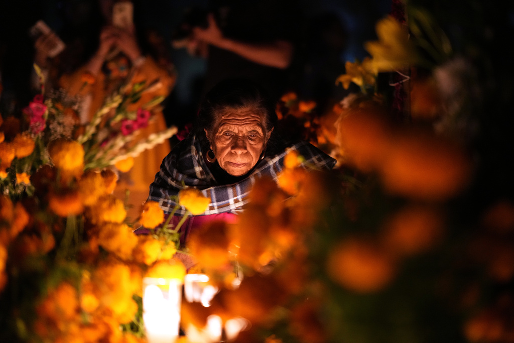 FILE - A woman sits next to the grave of a loved one during Day of the Dead celebrations at the cemetery of Tzintzuntzan, Mexico, Oct. 31, 2025. (AP Photo/Eduardo Verdugo, File)
