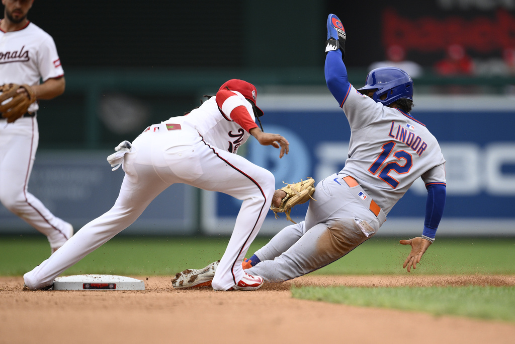 New York Mets' Francisco Lindor (12) is out while attempting to steal second base against Washington Nationals shortstop CJ Abrams, second from right, during the third inning of a baseball game, Thursday, Aug. 21, 2025, in Washington. (AP Photo/Nick Wass)