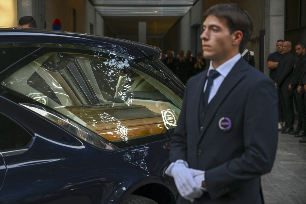 Staff of Giorgio Armani Spa gather outside the Armani/Teatro in Milan, northern Italy, as the hearse with the casket of designer Giorgio Armani, who died Thursday at age 91, leaves, Sunday, Sept. 7, 2025. (AP Photo/Nicola Marfisi)
