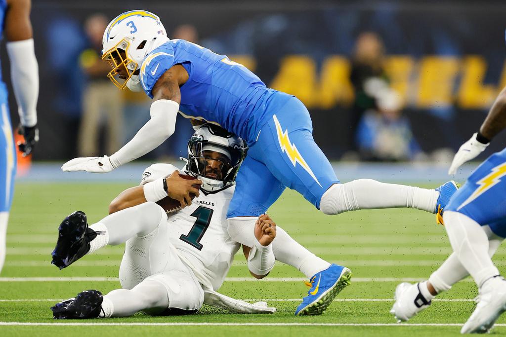 Philadelphia Eagles quarterback Jalen Hurts (1) slides under Los Angeles Chargers free safety Derwin James (3) during the first half of an NFL football game Monday, Dec. 8, 2025, in Inglewood, Calif. (AP Photo/Caroline Brehman)