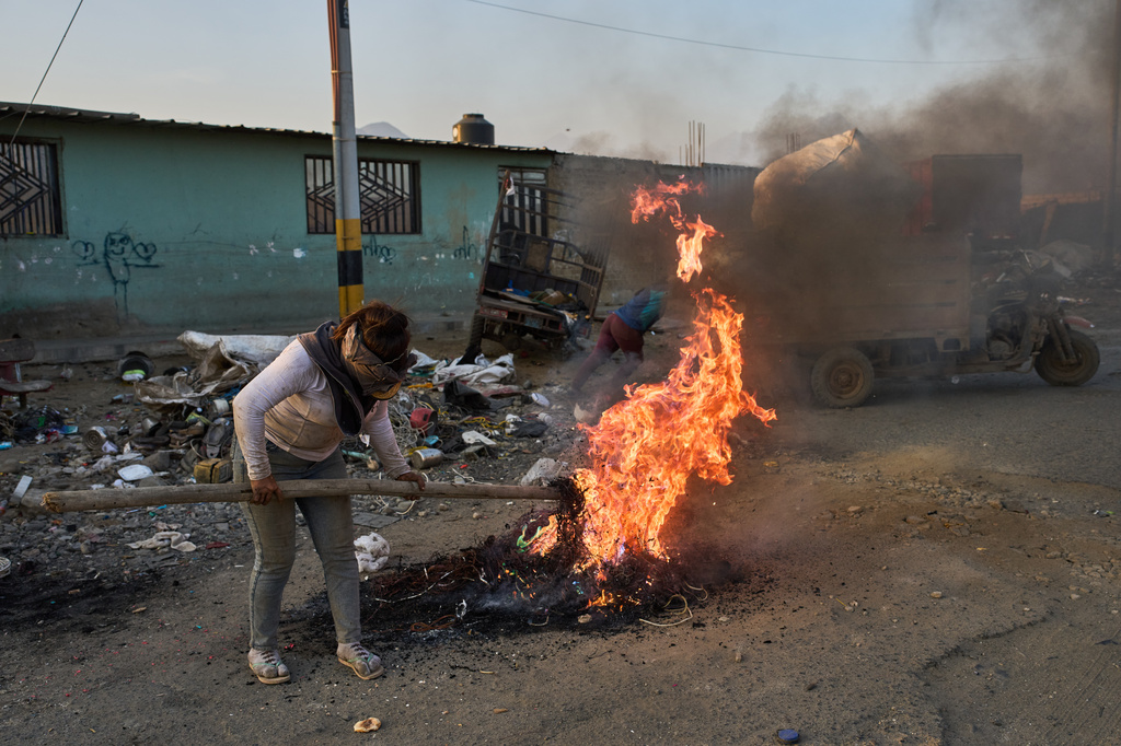 Giovana Rosas burns cables to extract copper for sale in the El Milagro district of Trujillo, Peru, Tuesday, May 26, 2026. (AP Photo/Rodrigo Abd)