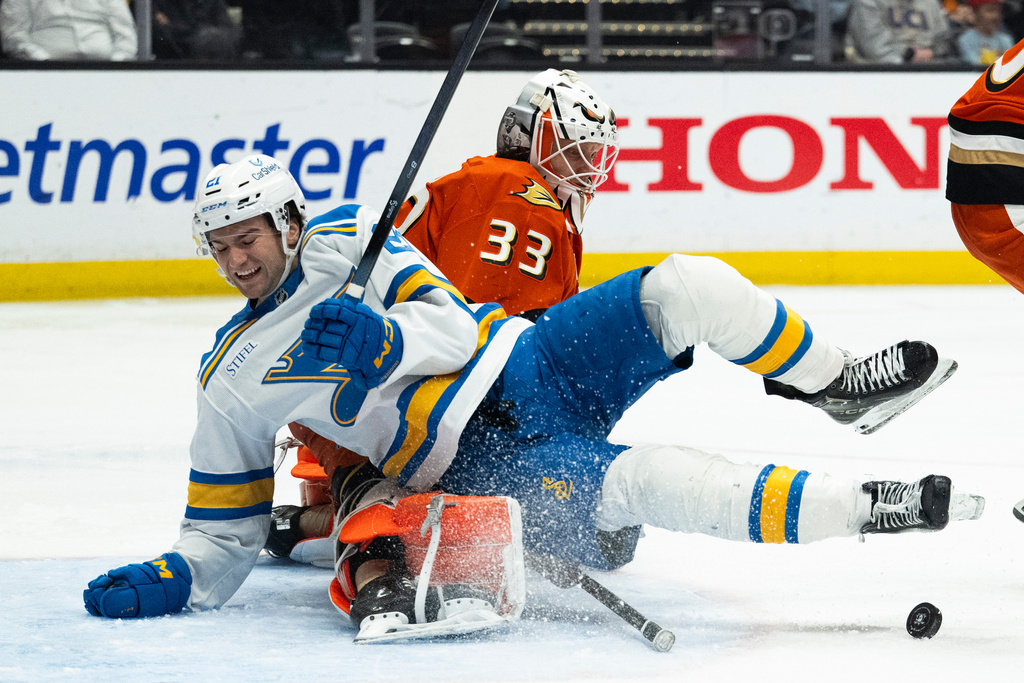 St. Louis Blues right wing Jimmy Snuggerud, front, skates into Anaheim Ducks goaltender Ville Husso during the second period of an NHL hockey game, Sunday, March 8, 2026, in Anaheim, Calif. (AP Photo/Kyusung Gong)