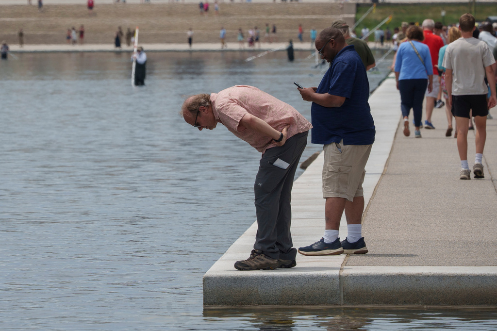 Visitors look into the Lincoln Memorial Reflecting Pool as National Park Service employees work in the background,Sunday, June 21, 2026, on the National Mall in Washington. (AP Photo/Jon Elswick)