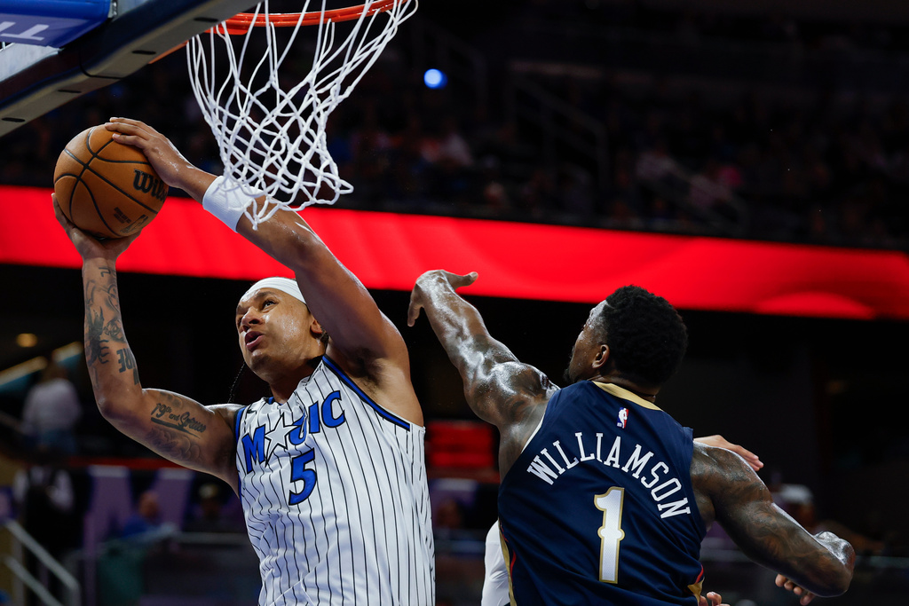Orlando Magic forward Paolo Banchero (5) goes up to shoot as he is defended by New Orleans Pelicans forward Zion Williamson (1) during the second half of an NBA basketball game Sunday, Jan. 11, 2026, in Orlando, Fla. (AP Photo/Kevin Kolczynski)