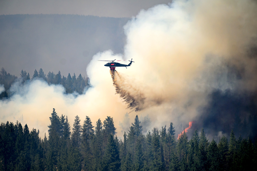 A helicopter drops water on the Akawa Butte fire on Friday, July 24, 2026, near Sisters, Ore. (AP Photo/Noah Berger)