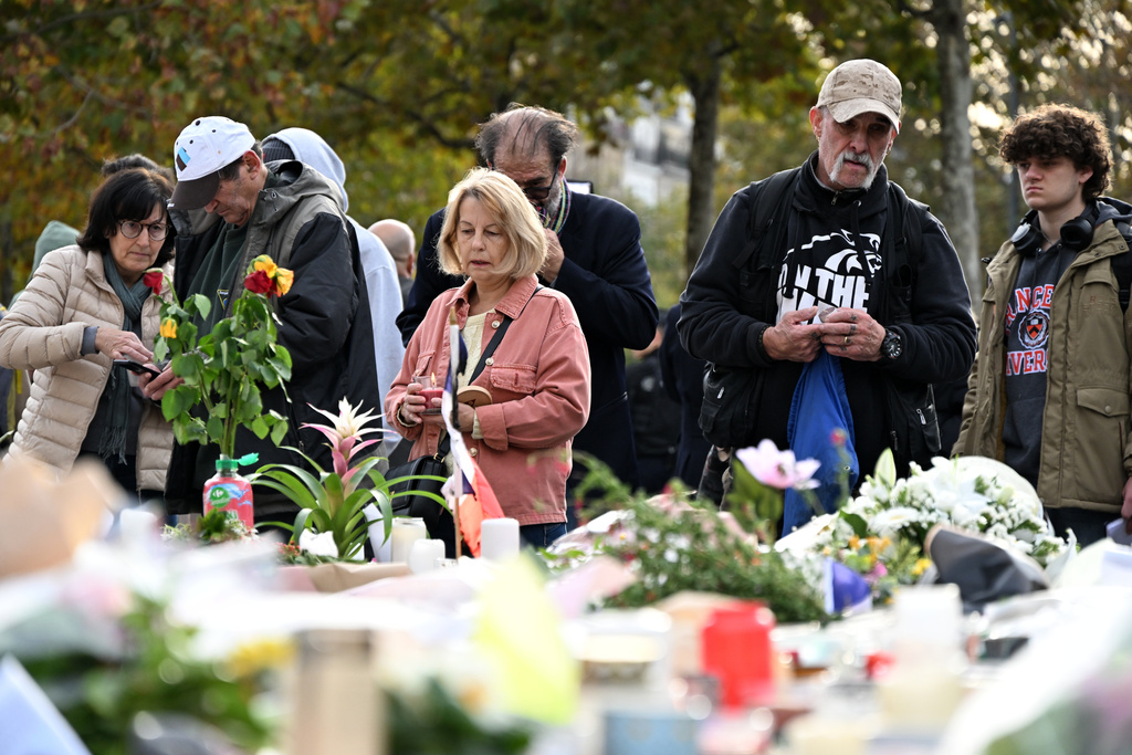 People watch flowers laid at the statue of the Place de la Republique (Republic Square) as Paris is marking the 10th anniversary of terrorist attacks that killed 132 people and injured hundreds, Thursday, Nov. 13, 2025 in Paris. (AP Photo/Emma Da Silva)