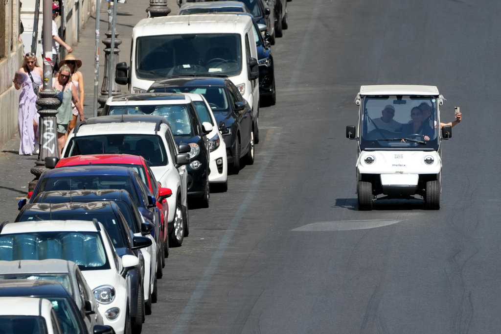 A golf cart carrying tourists travels past parked cars in Rome, Tuesday, Aug. 18, 2026, as city officials move to regulate the rapidly growing industry amid complaints about congestion, illegal parking, and overtourism. (AP Photo/Gregorio Borgia)