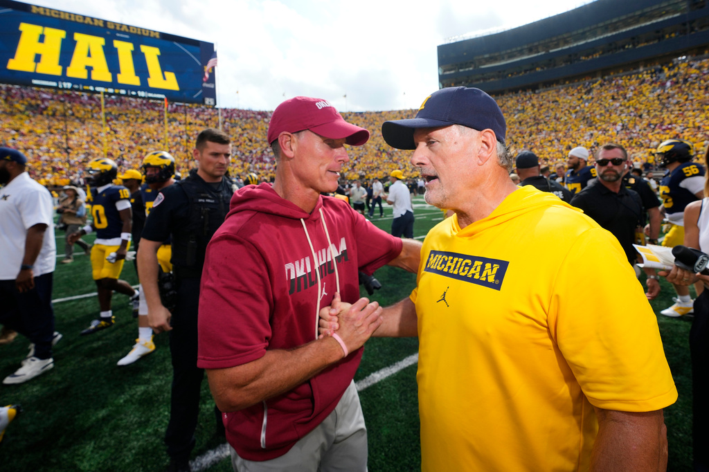 Oklahoma head coach Brent Venables, left, and Michigan head coach Kyle Whittingham, right, shake hands after an NCAA college football game Saturday, Sept. 12, 2026, in Ann Arbor, Mich. (AP Photo/Paul Sancya)