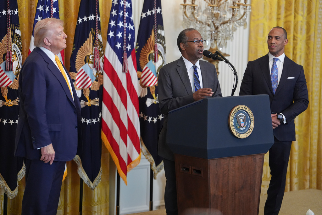 President Donald Trump and Housing and Urban Development Secretary Scott Turner, right, listen as former Housing and Urban Development Secretary Dr. Ben Carson speaks during a Black History Month event in the East Room of the White House, Wednesday, Feb. 18, 2026, in Washington. (AP Photo/Evan Vucci)