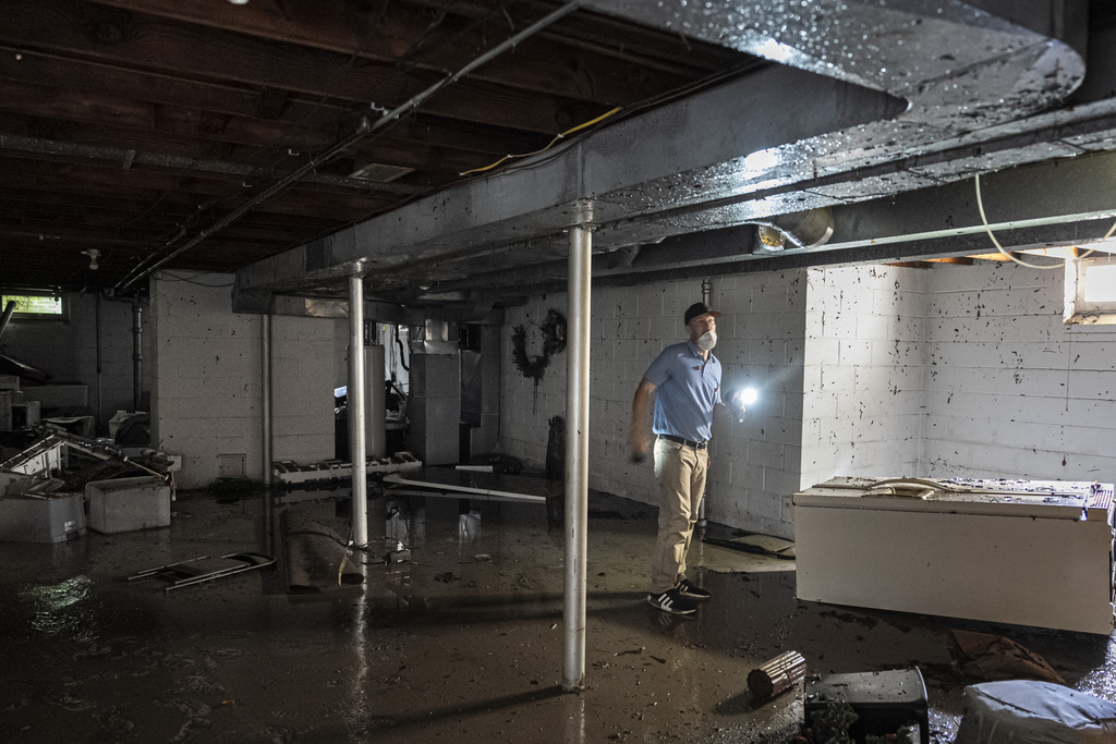 A structural engineer surveys a friend's home with flooding, Monday, Aug. 11, 2025, in Wauwatosa, Wis. (AP Photo/Andy Manis)