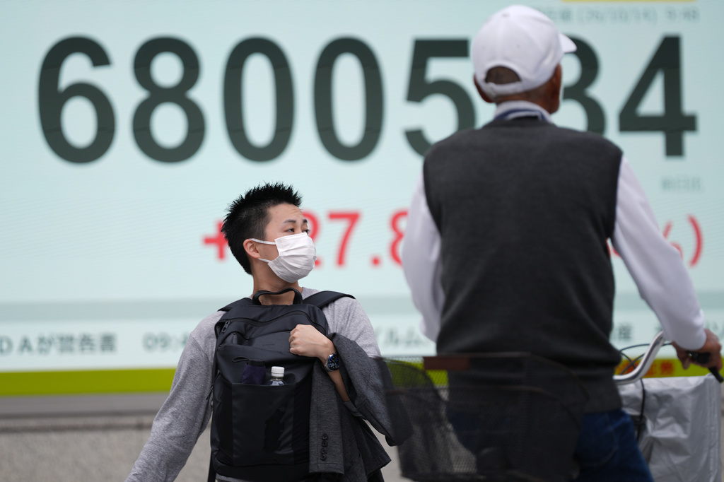 People pass an electronic board displaying Japan's Nikkei stock index at a securities firm Wednesday, Oct. 14, 2026, in Tokyo. (AP Photo/Eugene Hoshiko)