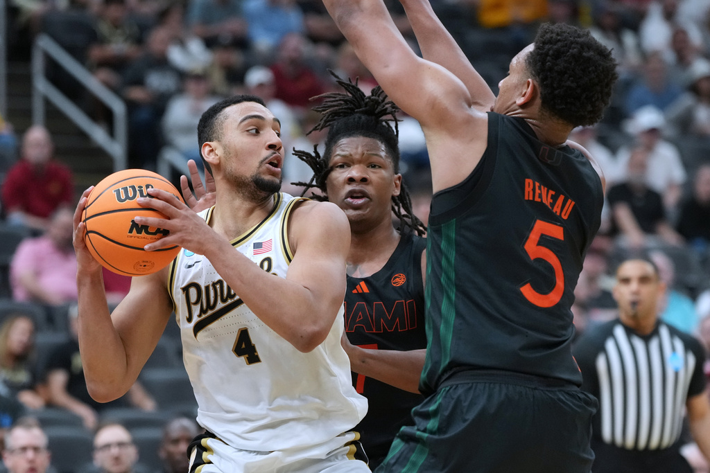 Purdue's Trey Kaufman-Renn (4) looks to pass as Miami's Shelton Henderson and Malik Reneau (5) defend during the first half in the second round of the NCAA college basketball tournament, Sunday, March 22, 2026, in St. Louis. (AP Photo/Jeff Roberson)