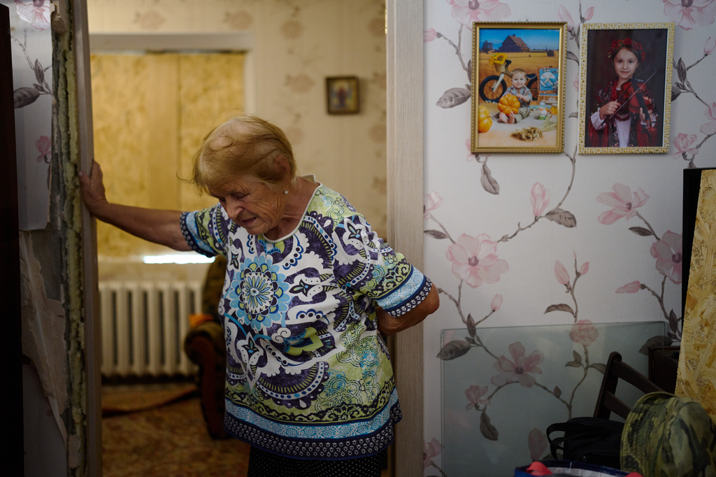 Valentyna Svertoka, 86, leans against a doorframe as she cleans her apartment in a partially damaged residential building the day after a Russian missile and drone attack in Kyiv, Friday, Aug. 21, 2026. (AP Photo/Francisco Seco)