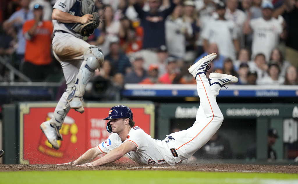 Houston Astros' Jacob Melton dives home to score a run on Yordan Alvarez's RBI single as New York Yankees catcher Austin Wells jumps up to try to defend the plate during the seventh inning of a baseball game Wednesday, Sept. 3, 2025, in Houston. (AP Photo/Karen Warren)