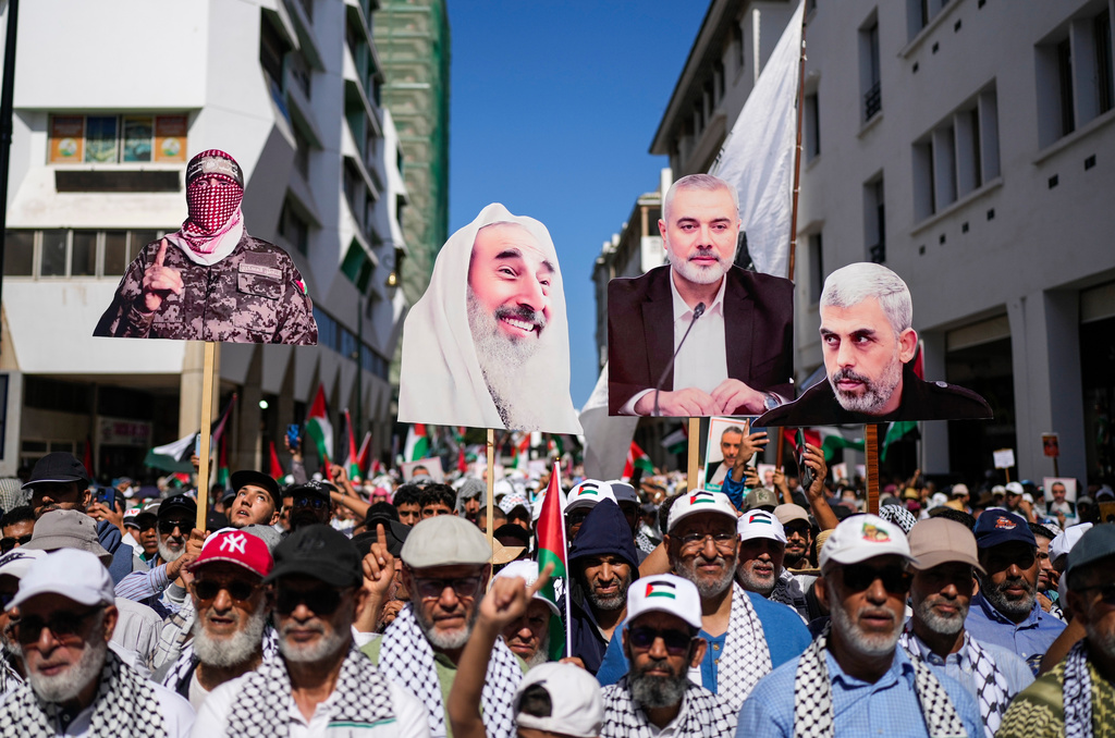 People carry photos of Hamas leaders as tens of thousands take part in a march in support of Palestinians in Gaza and against normalization with Israel, in Rabat, Morocco, Sunday, Oct. 5, 2025. (AP Photo/Mosa'ab Elshamy)