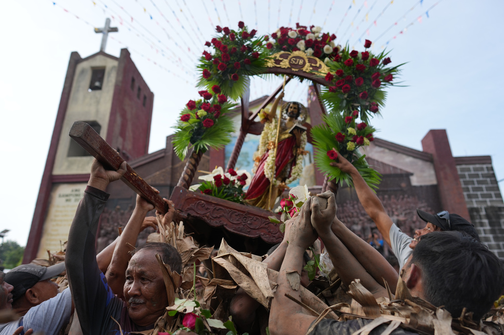 Catholic devotees covered in mud and dried banana leaves participate in the mud people festival on the feast day of Saint John the Baptist at Bibiclat, Nueva Ecija province, northern Philippines on Wednesday, June 24, 2026. (AP Photo/Aaron Favila)