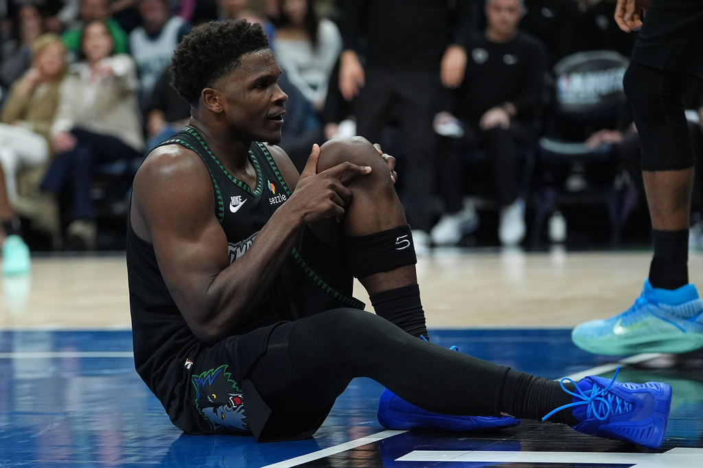 Minnesota Timberwolves guard Anthony Edwards grabs his knee after an injury during the first half of Game 4 of a first-round NBA basketball playoff series against the Denver Nuggets, Saturday, April 25, 2026, in Minneapolis. (AP Photo/Abbie Parr)