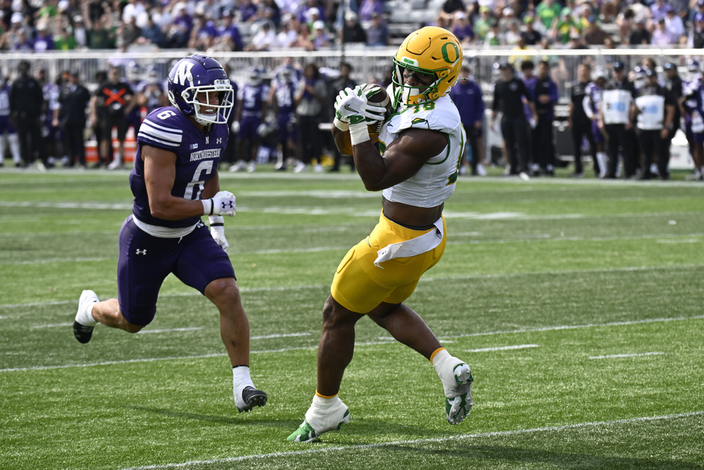 Oregon tight end Kenyon Sadiq (18) catches a touchdown pass as Northwestern defensive back Robert Fitzgerald (6) looks on during the first half of an NCAA college football game on Saturday, Sept. 13, 2025 in Evanston, Ill. (AP Photo/Matt Marton)