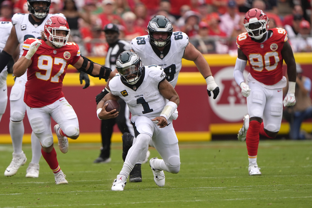 Philadelphia Eagles quarterback Jalen Hurts (1) scrambles as Kansas City Chiefs defensive end Ashton Gillotte (97) and defensive end Charles Omenihu (90) give chase during the first half of an NFL football game Sunday, Sept. 14, 2025, in Kansas City, Mo. (AP Photo/Charlie Riedel)